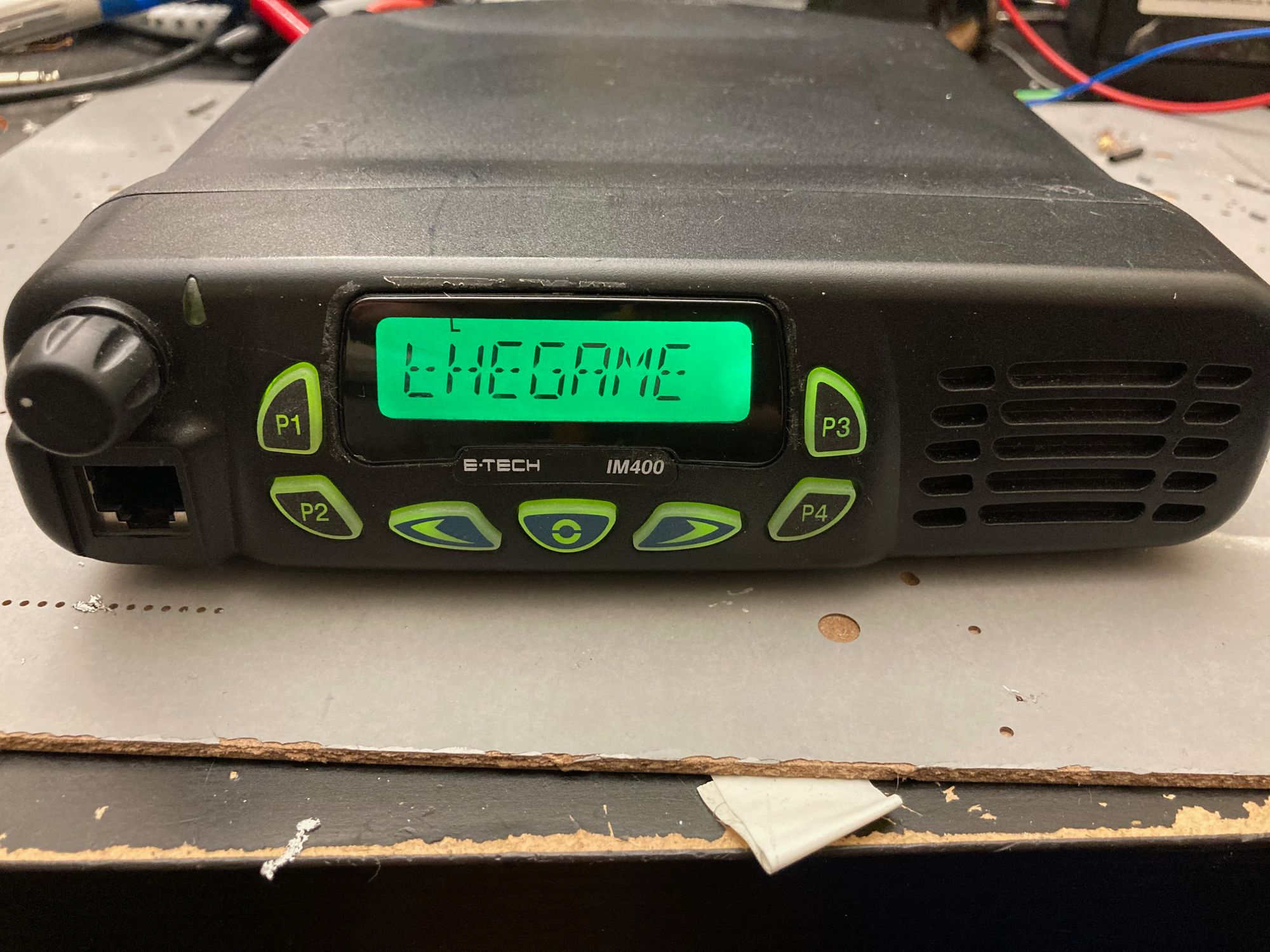 A black mobile radio sits on a desk with text "thegame" on the screen